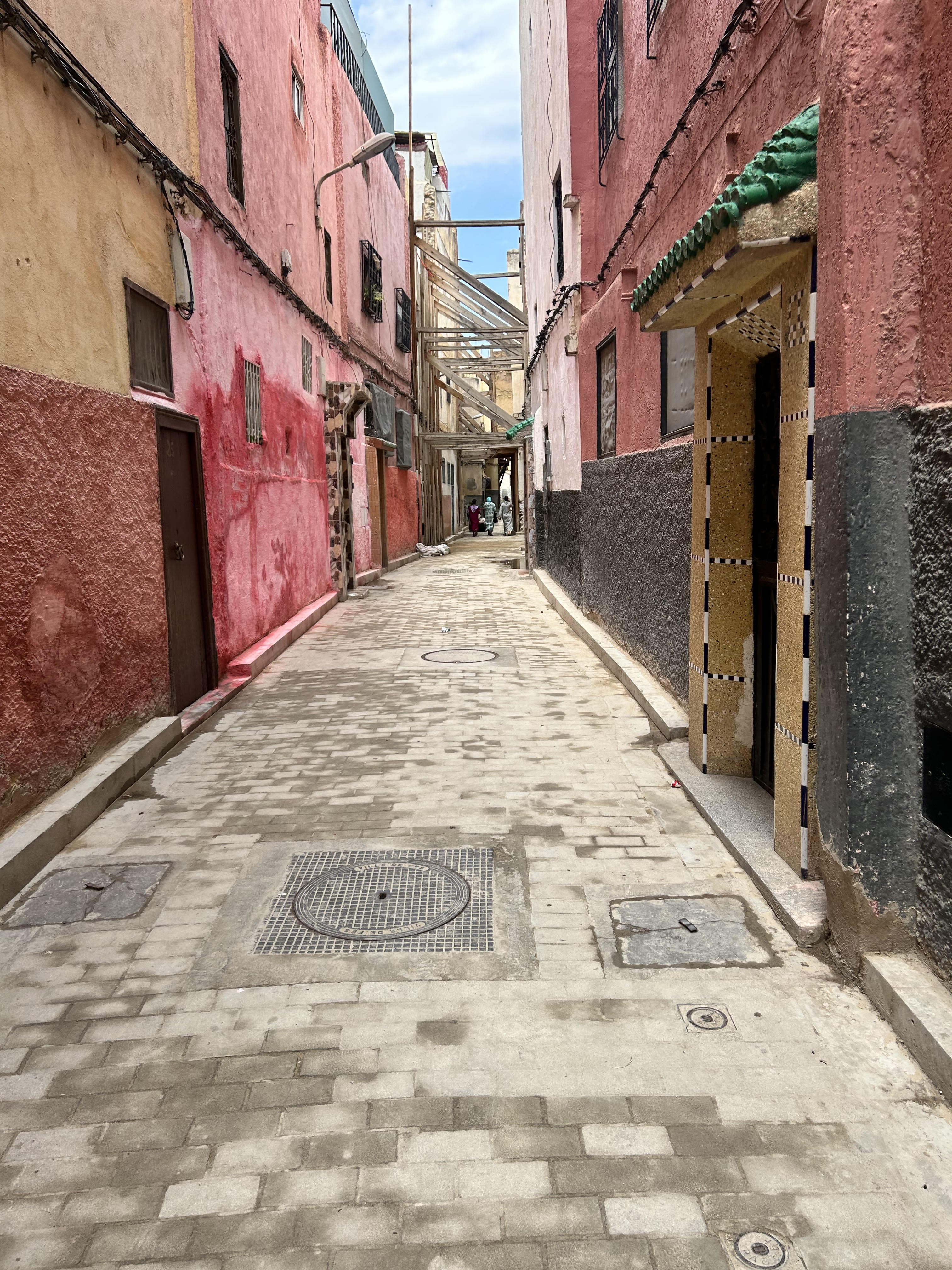 Alleyway in Fes with colorful walls and brick road.